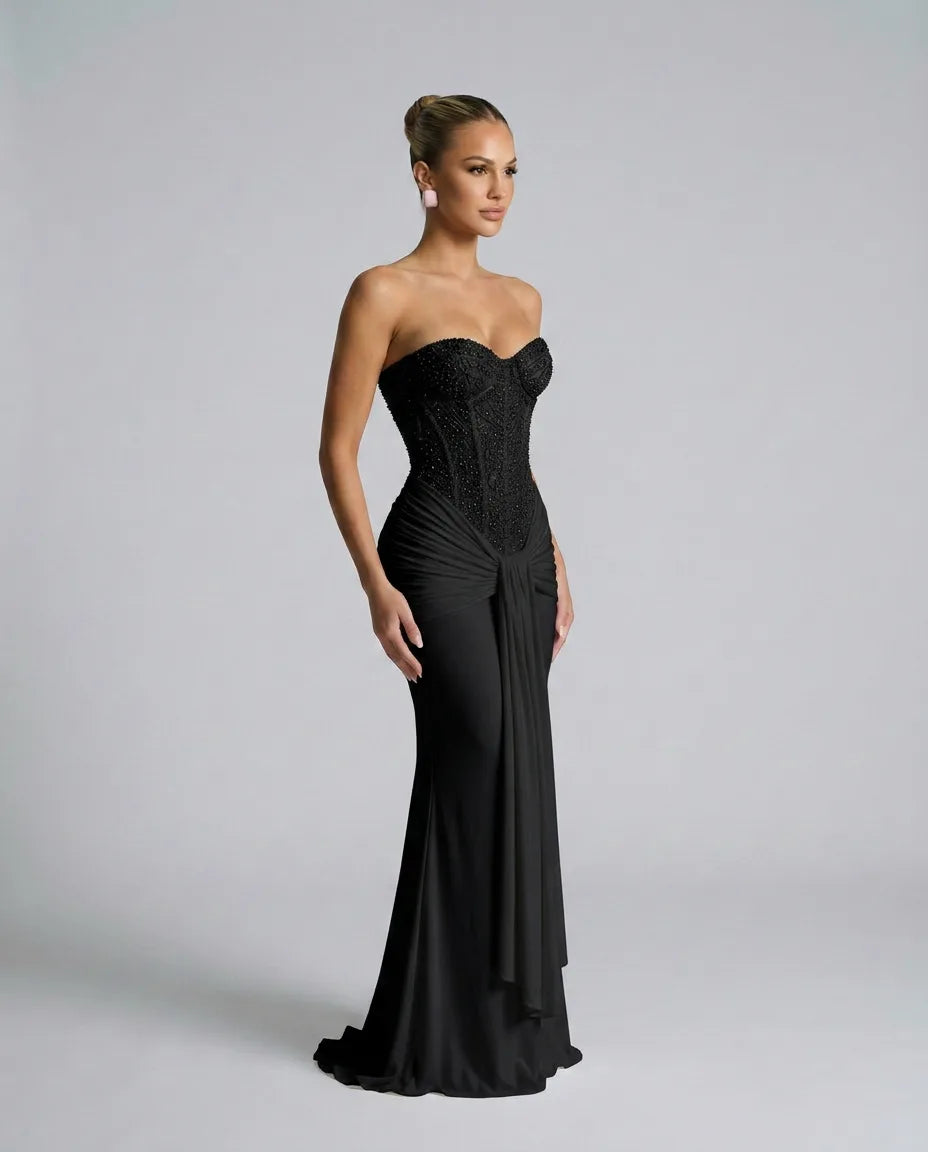 Side profile of the black sequin corset gown showing the fitted boned bodice and gathered fabric knot at the waist