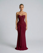 Front view of a strapless burgundy sequined evening gown with beaded bustier top and flowing mermaid-style skirt