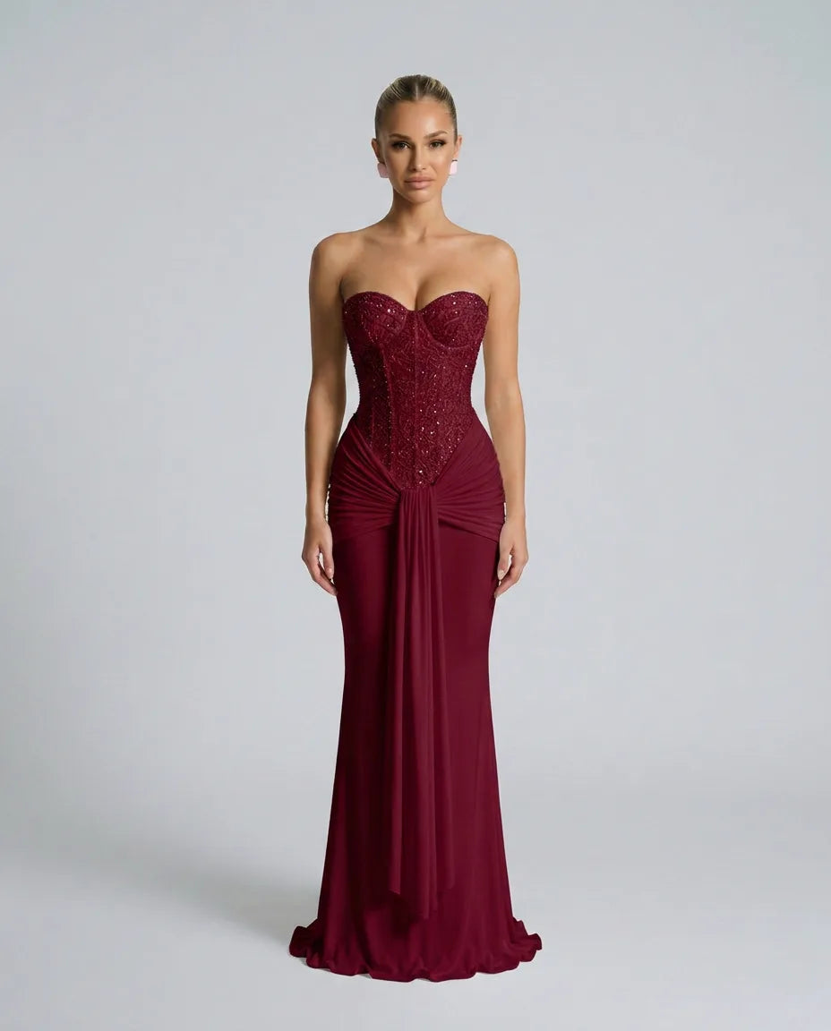 Front view of a strapless burgundy sequined evening gown with beaded bustier top and flowing mermaid-style skirt