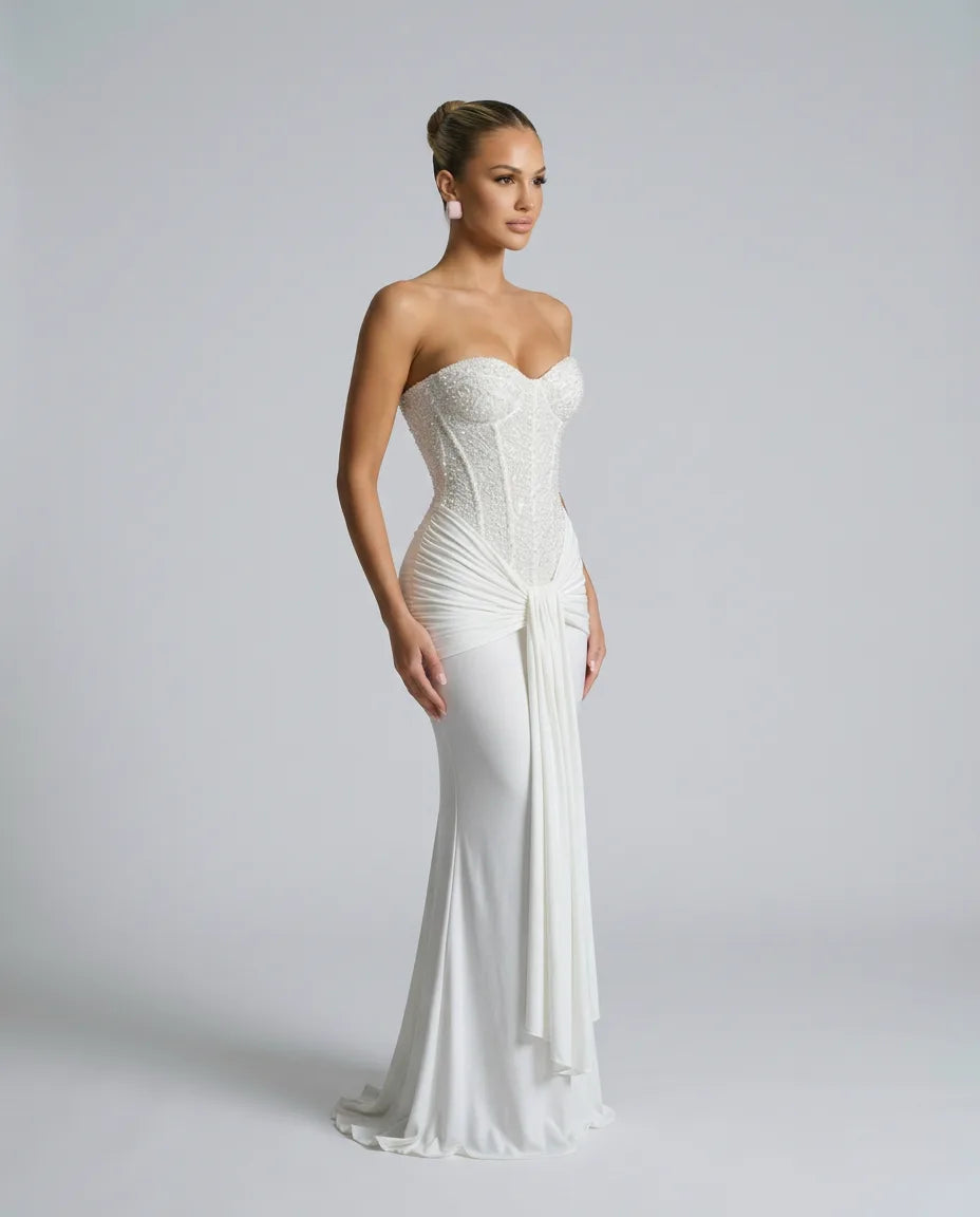 Side view of the white sequin bustier gown showing the structured corset seams and draped sash at the hip