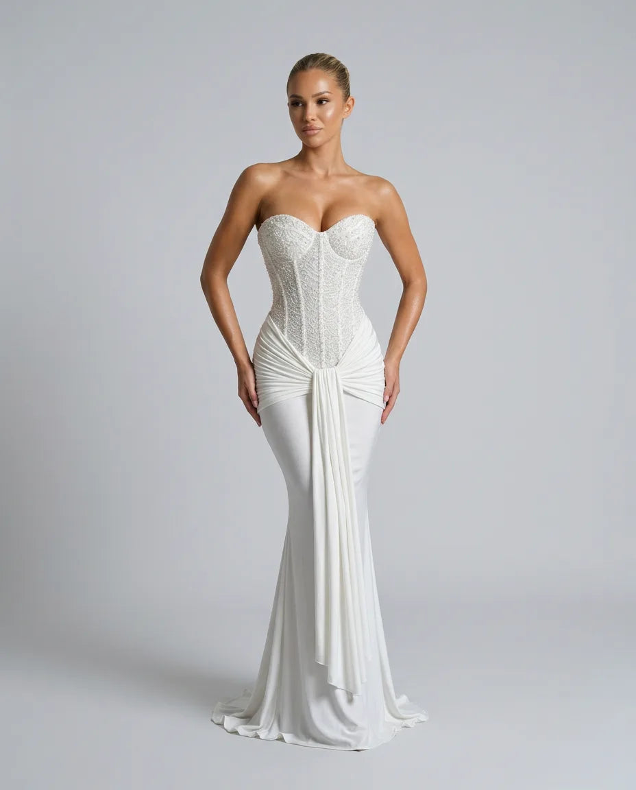Close front view of the white strapless gown highlighting the sequined corset bodice, sweetheart neckline and waist drape