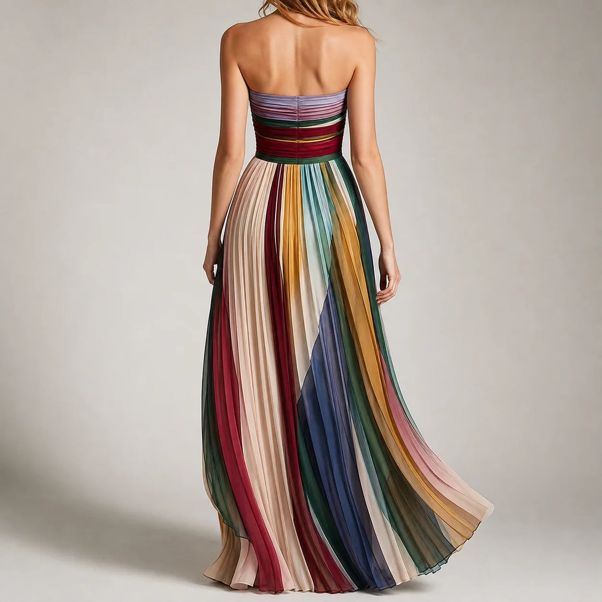 Back view showing the strapless straight neckline and flowing pleated multicolour skirt sweeping to the floor