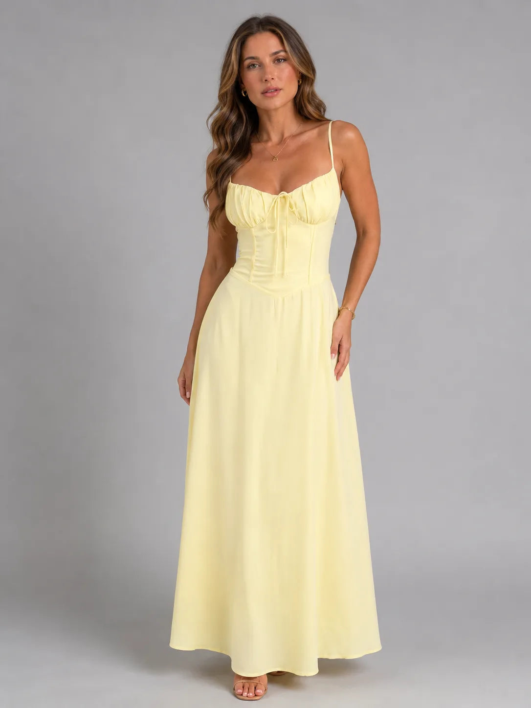 Front view of model in pale yellow strappy maxi dress with ruched sweetheart bodice and tie detail