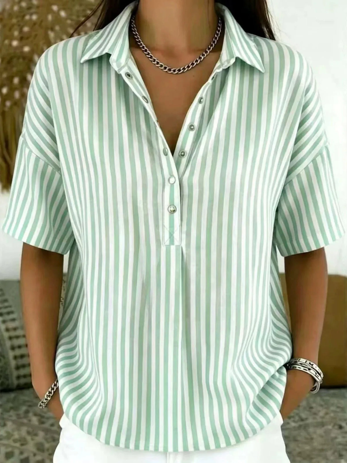 Close-up front view of a light green and white vertical striped blouse with collar and half-button placket