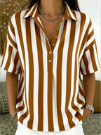 Close view of striped blouse neckline with collar, metal buttons and layered chain necklaces