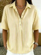 Yellow and white striped collared blouse with half-button front, styled with white pants and silver bracelet
