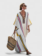 Cream maxi dress with bold pink, yellow and navy stripes, embroidered V-neck trim and front patch pocket, styled with pink earrings