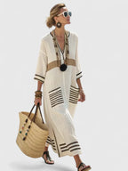 Ivory maxi dress with brown horizontal colour-block trim and striped pockets, paired with a beaded tassel necklace