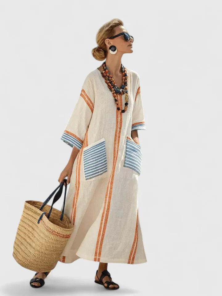 Cream maxi dress with orange vertical stripes and contrast blue-striped pockets, worn with layered boho beaded necklaces