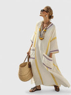Cream maxi dress with yellow stripes and lilac trim, striped pockets, styled with pom-pom beaded necklace and straw bag