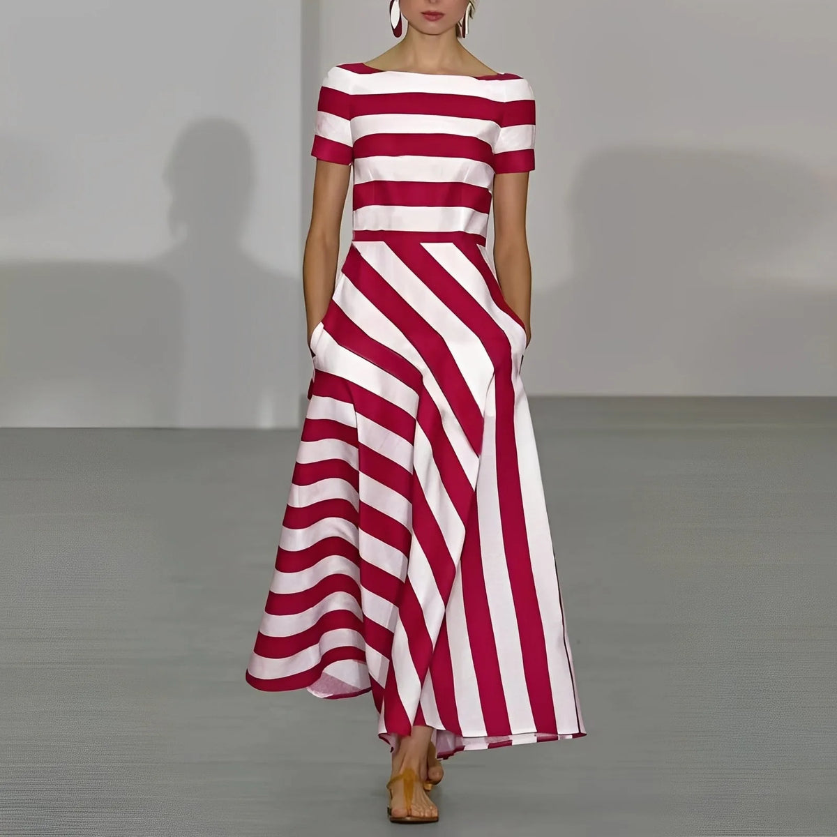 Model walks a runway in a red and white striped maxi dress with boat neckline, short sleeves and fitted bodice