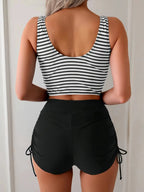 Back view of navy and white striped tankini top with scoop back worn over black high-waisted ruched shorts