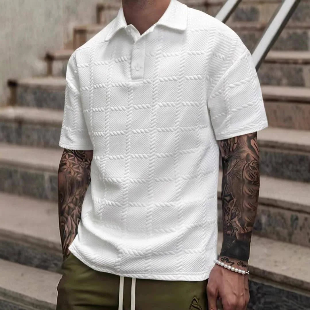 Front view of man wearing white textured knit polo shirt with woven windowpane pattern and button placket, on stone steps