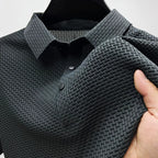 Close-up of a charcoal grey textured polo shirt on a hanger, showing the woven collar and button placket.