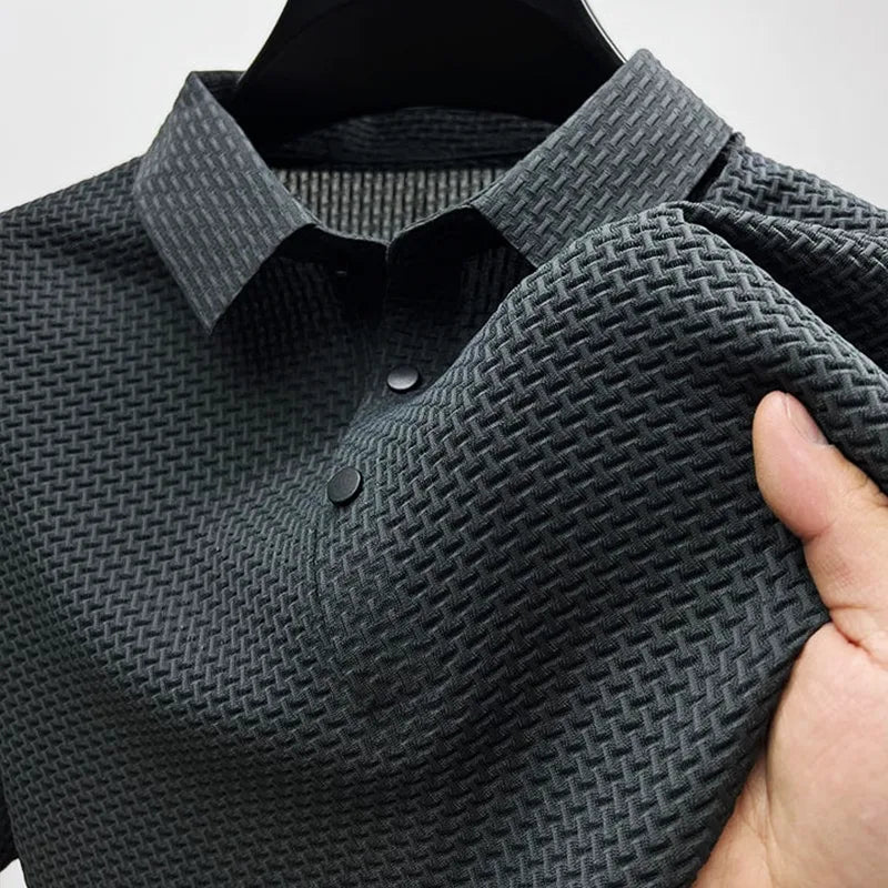 Close-up of a charcoal grey textured polo shirt on a hanger, showing the woven collar and button placket.