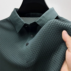 Dark green textured polo shirt on a hanger with a close view of the collar, buttons and fabric weave.