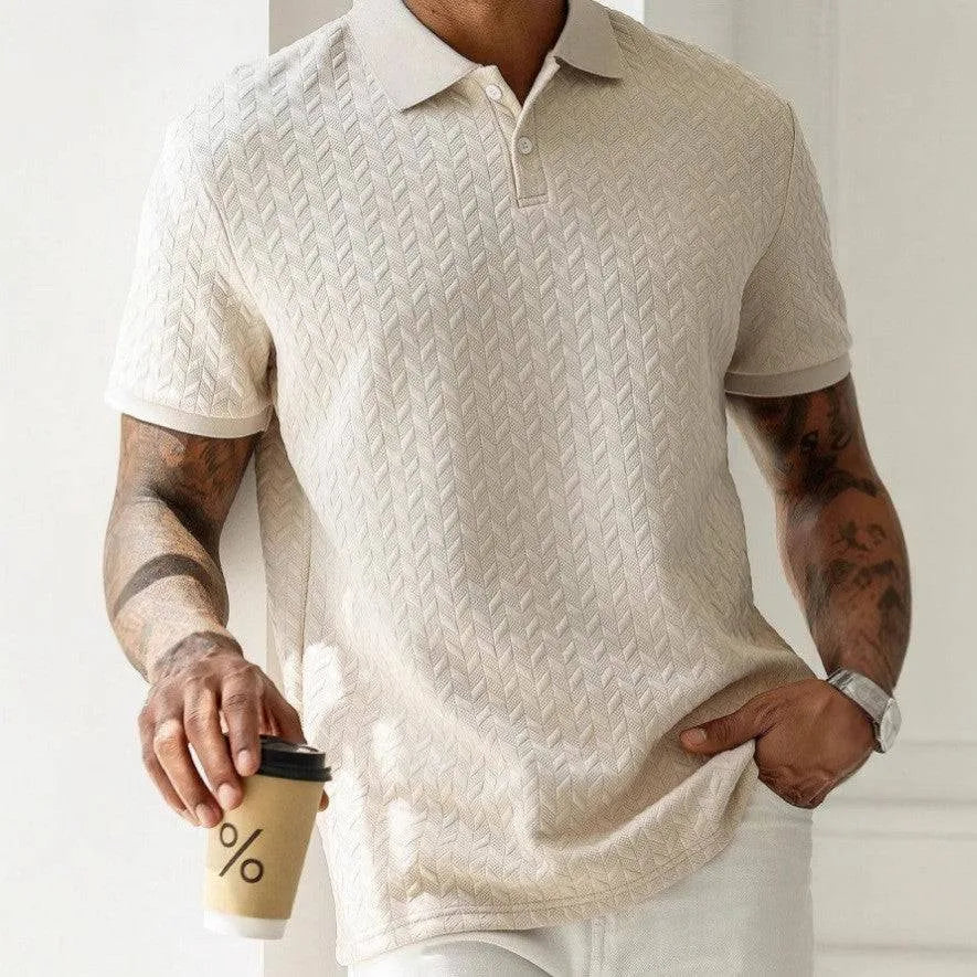 Man wearing apricot textured knit polo shirt with herringbone pattern, holding a coffee cup, front view close up