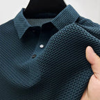 Dark navy textured polo shirt on a hanger, close-up of the collar, snap buttons and woven sleeve fabric.