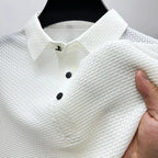 White textured polo shirt on a hanger, showing the collar, button placket and the fabric texture up close.