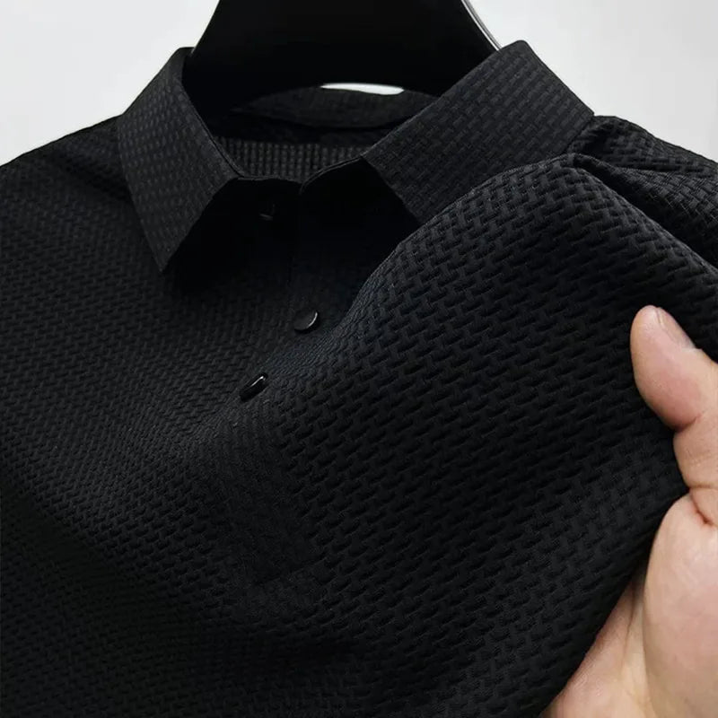 Black textured polo shirt on a hanger, close-up of the collar, buttons and the woven fabric texture of the sleeve.