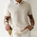 Front detail of apricot textured polo shirt worn tucked, showing herringbone knit pattern and two-button placket