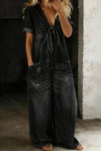 Faded black denim jumpsuit with tie-front neckline, rolled cuffs and front patch pockets on a model