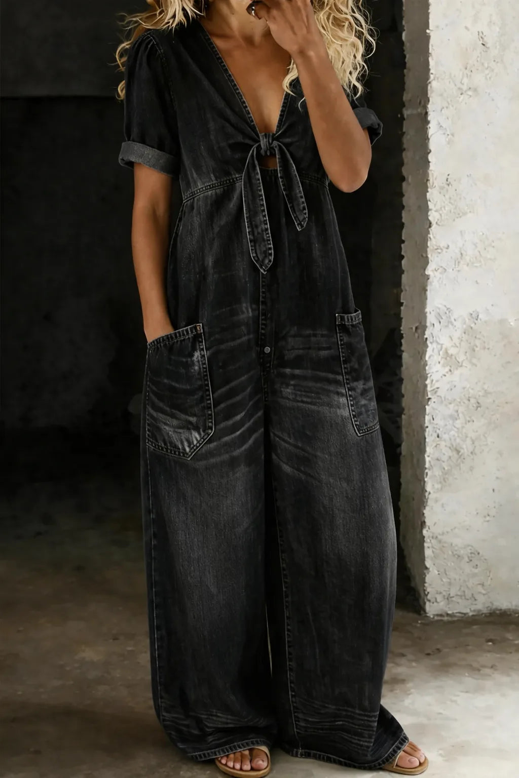 Faded black denim jumpsuit with tie-front neckline, rolled cuffs and front patch pockets on a model