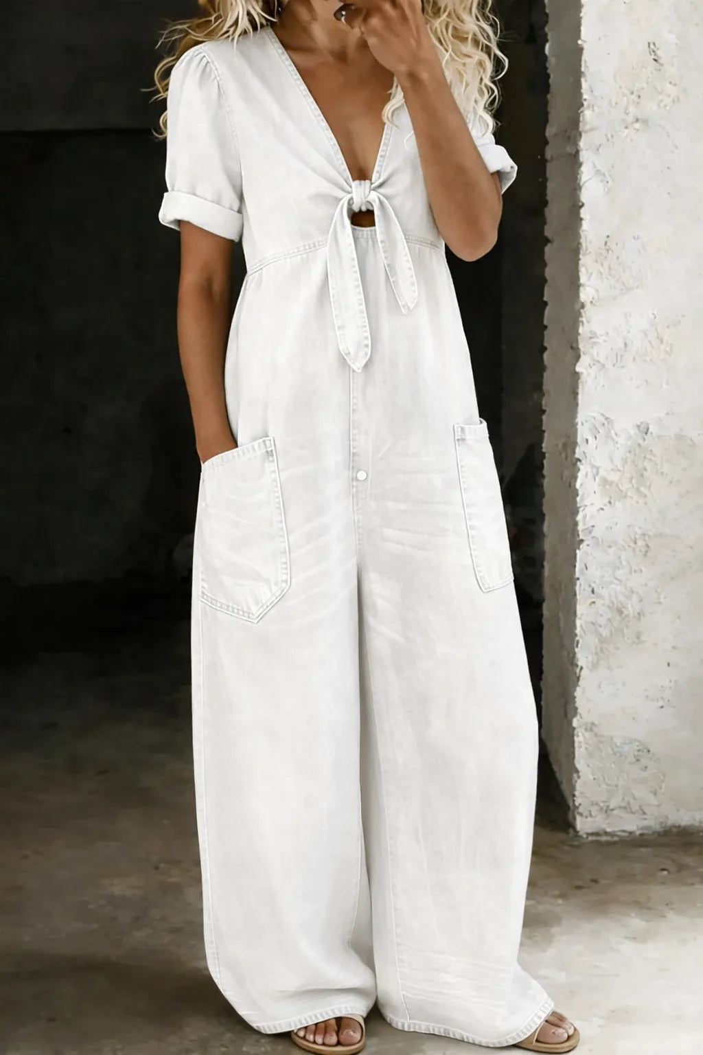 Off-white denim jumpsuit with tie-front neckline, rolled short sleeves and wide-leg silhouette