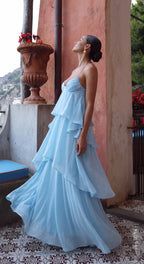 Side profile of a baby blue tiered chiffon maxi dress flowing in motion on a terracotta terrace