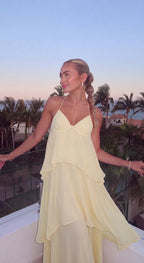 Butter yellow tiered maxi dress with halter neckline worn on a balcony overlooking palm trees at sunset