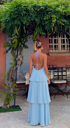 Back view of a baby blue maxi dress showing the open back, halter tie and cascading tiered skirt