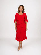 Front view of a woman in a red tiered ruffle midi dress with cape sleeves, paired with nude pointed heels