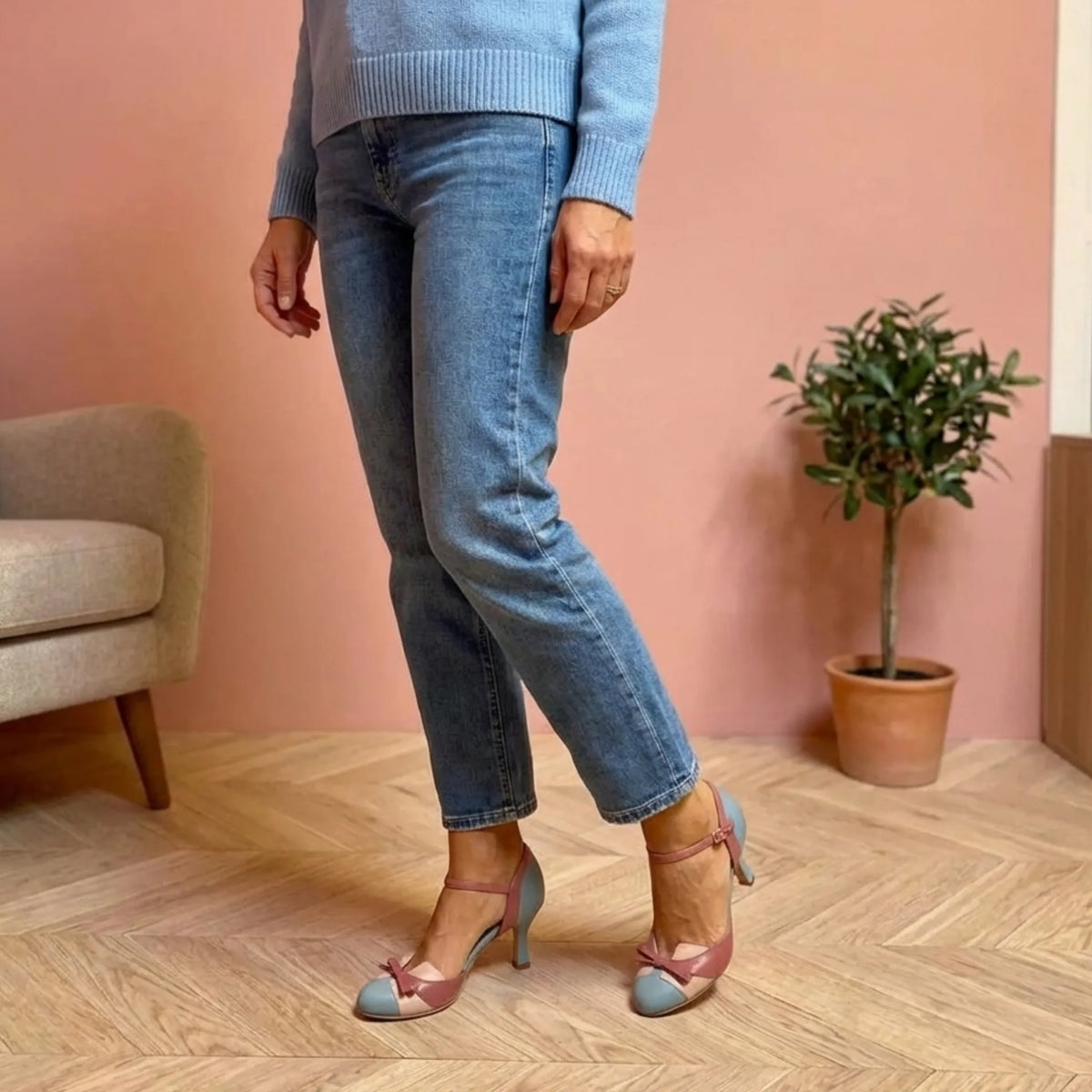 Full-length view of a woman wearing light blue and dusty rose two-tone heels with straight-leg jeans and a jumper