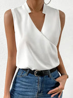 Close-up front view of a white sleeveless wrap-style top with a notched V-neckline, worn with a black belt and jeans