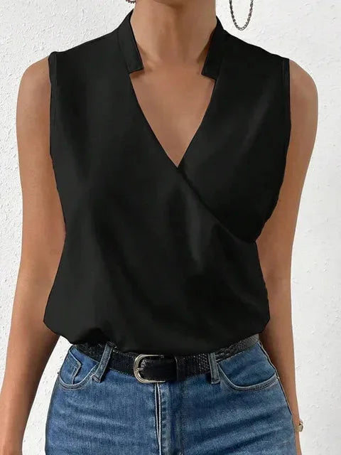 Close-up of a black sleeveless wrap top showing the notched V-neckline and smooth, lightly draped fabric