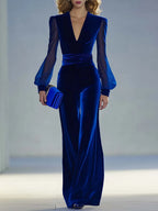 Front view of model in deep royal blue velvet jumpsuit with plunging V-neckline and sheer mesh long sleeves