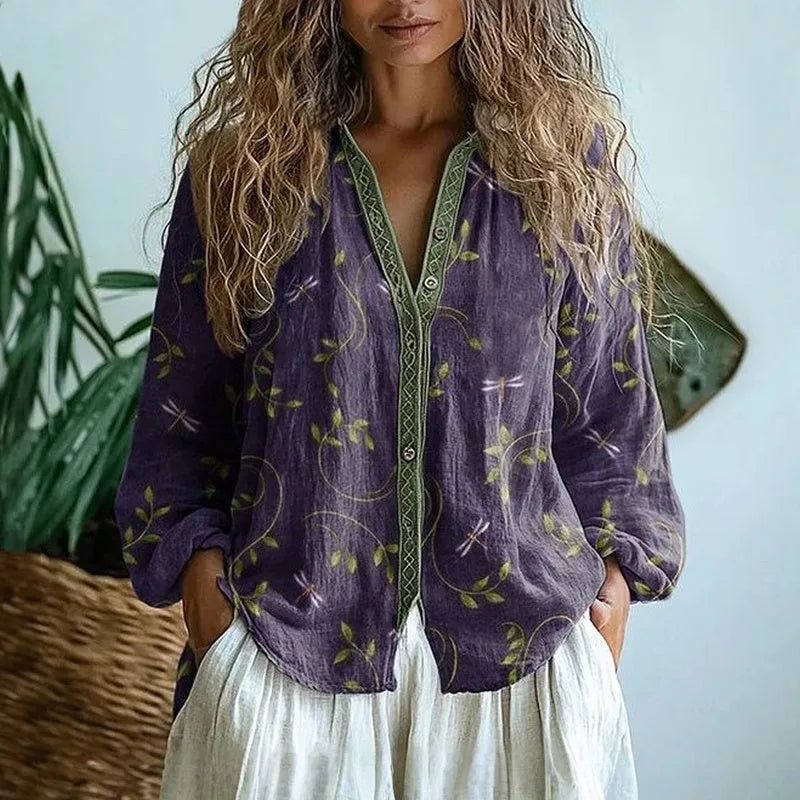Close-up front view of purple leaf and dragonfly print shirt with green V-neck trim and button closure