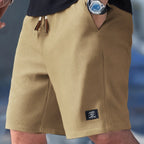 Khaki waffle-textured shorts with contrast drawstring and small logo tab near the hem