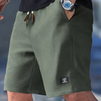 Olive green waffle-knit shorts with brown leather cord ends and relaxed drop-shoulder fit