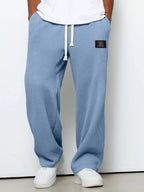 Close-up front angle of sky blue waffle-textured pants showing adjustable drawstring waistband and patch detail