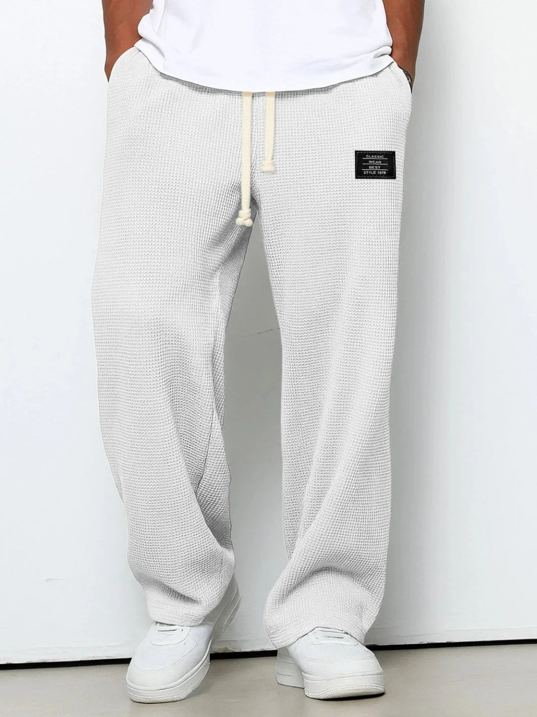 White waffle-knit relaxed pants worn with white sneakers, front view against plain backdrop