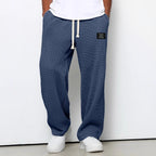 Denim blue waffle-knit relaxed pants worn with white sneakers, full front view