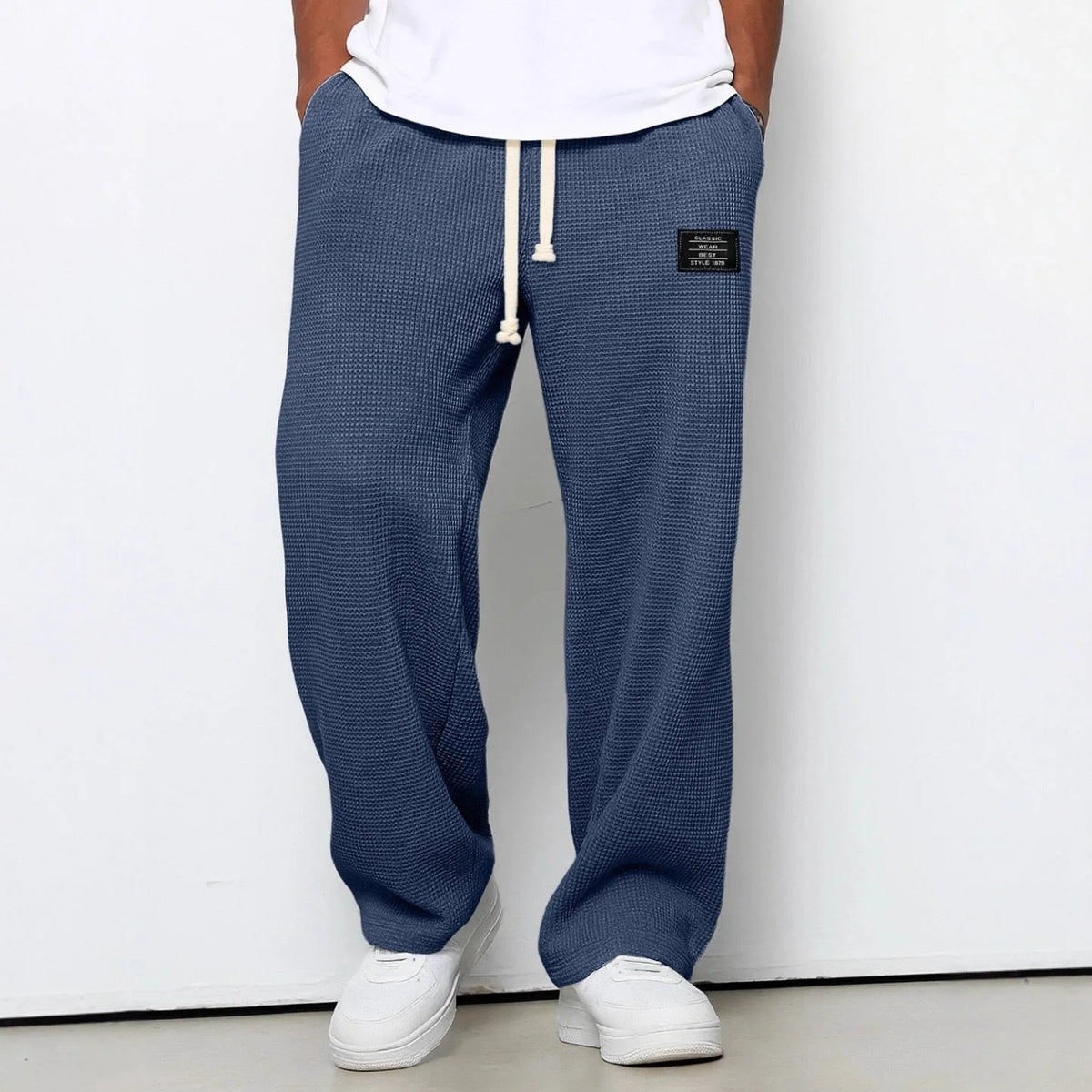 Denim blue waffle-knit relaxed pants worn with white sneakers, full front view