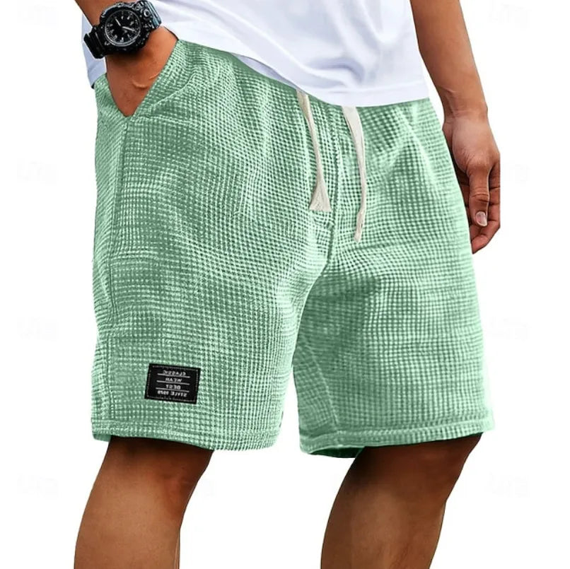 Sage green textured waffle shorts on a model, side angle highlighting slanted pocket and loose fit