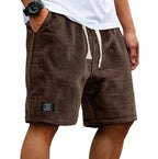 Dark brown waffle-textured shorts on a model, side profile showing relaxed fit and woven patch detail
