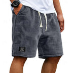 Charcoal grey waffle-knit shorts on a model, side view with slanted pocket and cream drawstring cord