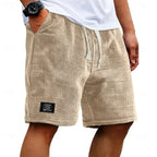 Close-up front angle of beige waffle shorts showing textured fabric weave and fabric patch label on leg