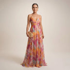 Woman in a multicolour floral chiffon maxi dress with wrap bodice and thin straps, standing against a neutral backdrop