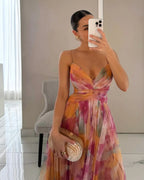Close-up mirror selfie of a wrap maxi dress in orange and pink watercolour print, showing the crossover bodice detail