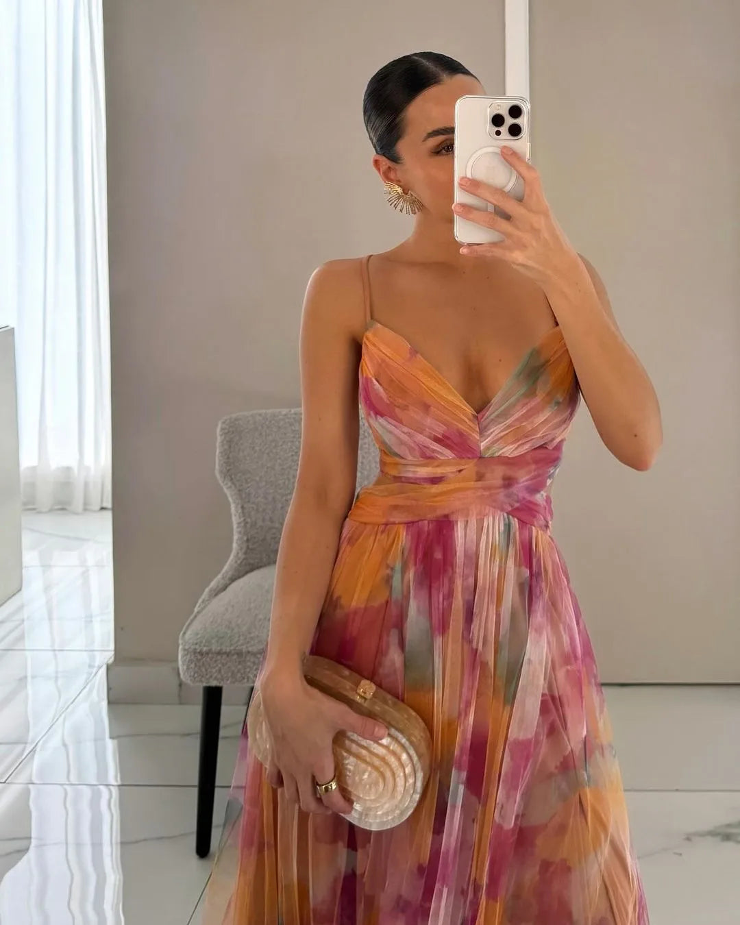Close-up mirror selfie of a wrap maxi dress in orange and pink watercolour print, showing the crossover bodice detail